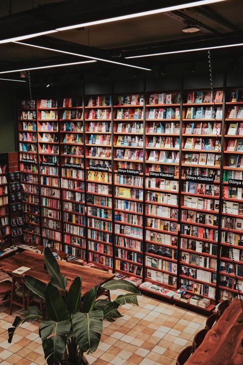 Free Warm and inviting bookstore interior featuring wooden shelves filled with books and cozy reading spaces. Stock Photo