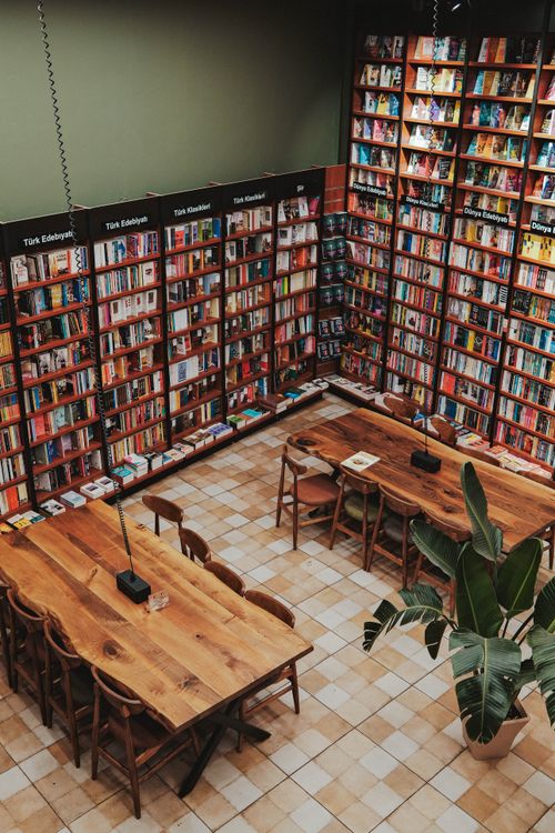 Free A cozy bookstore featuring wooden tables and bookshelves filled with colorful books. Stock Photo