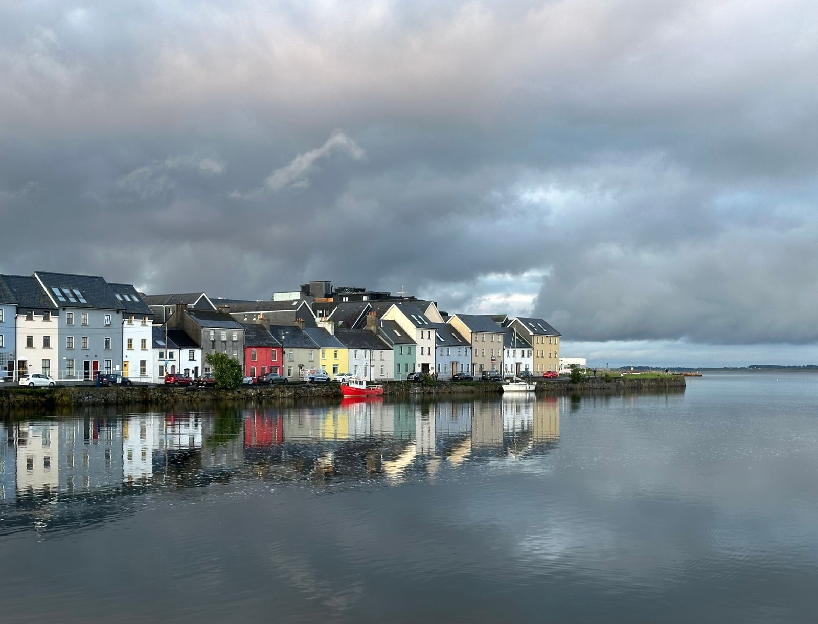 Galway houses reflecting in calm waters under a moody sky