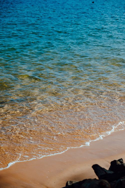 Free Peaceful shoreline with gently lapping waves and clear blue waters on a sunny day. Stock Photo