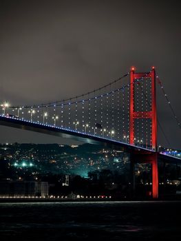 Stunning night view of the Bosphorus Bridge in Istanbul with illuminated lights and vibrant colors.