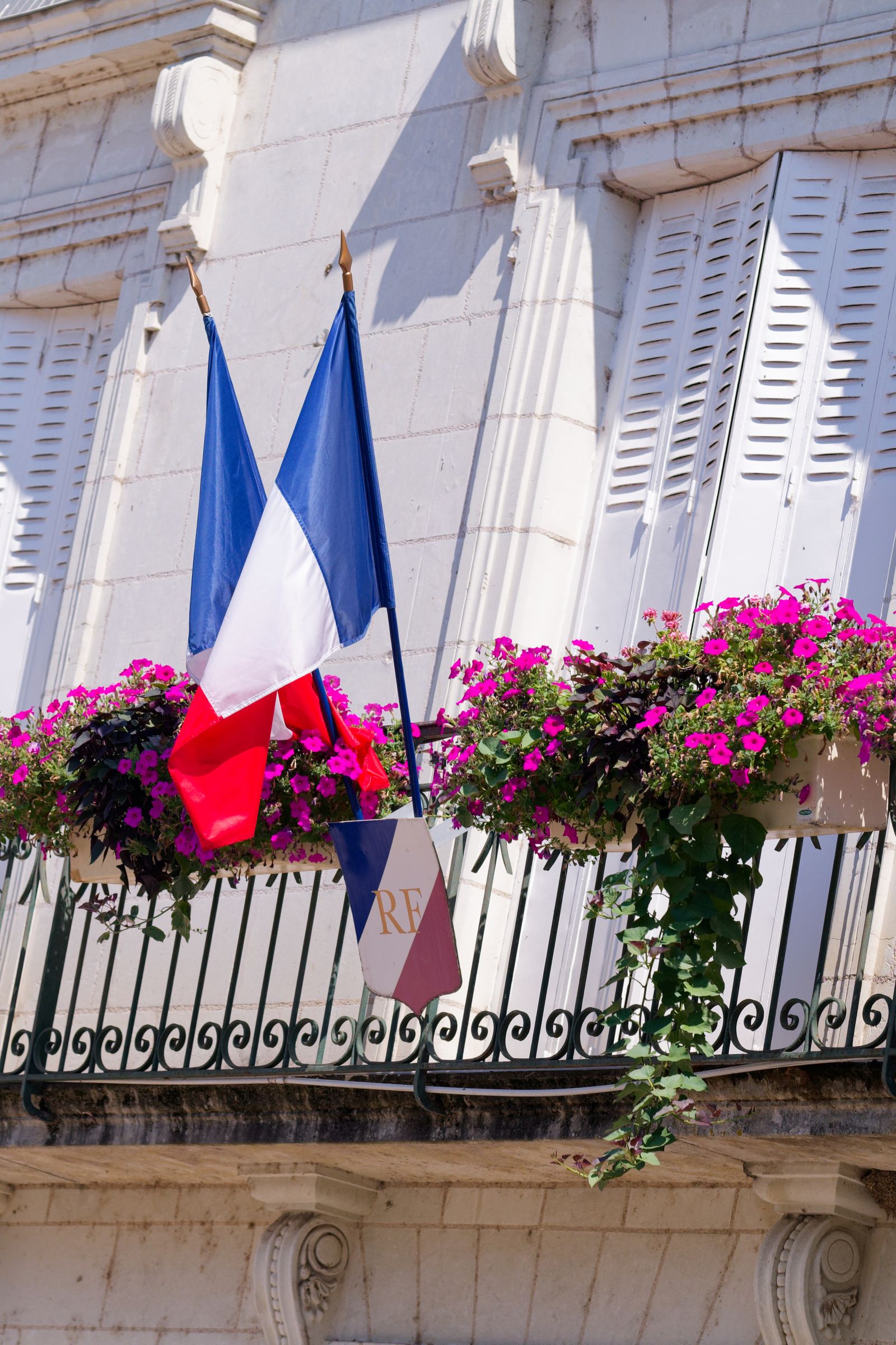Des drapeaux français célèbrent le 14 juillet sur un balcon fleuri de mairie