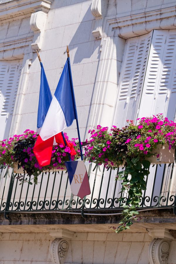 Des drapeaux français célèbrent le 14 juillet sur un balcon fleuri de mairie