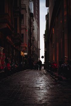 Dimly lit urban alleyway with people and motorcycles creating a mysterious mood at twilight.