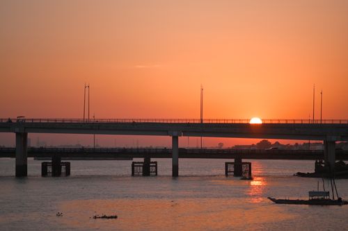 Free Beautiful sunset behind an urban bridge over a calm river, creating a serene silhouette. Stock Photo