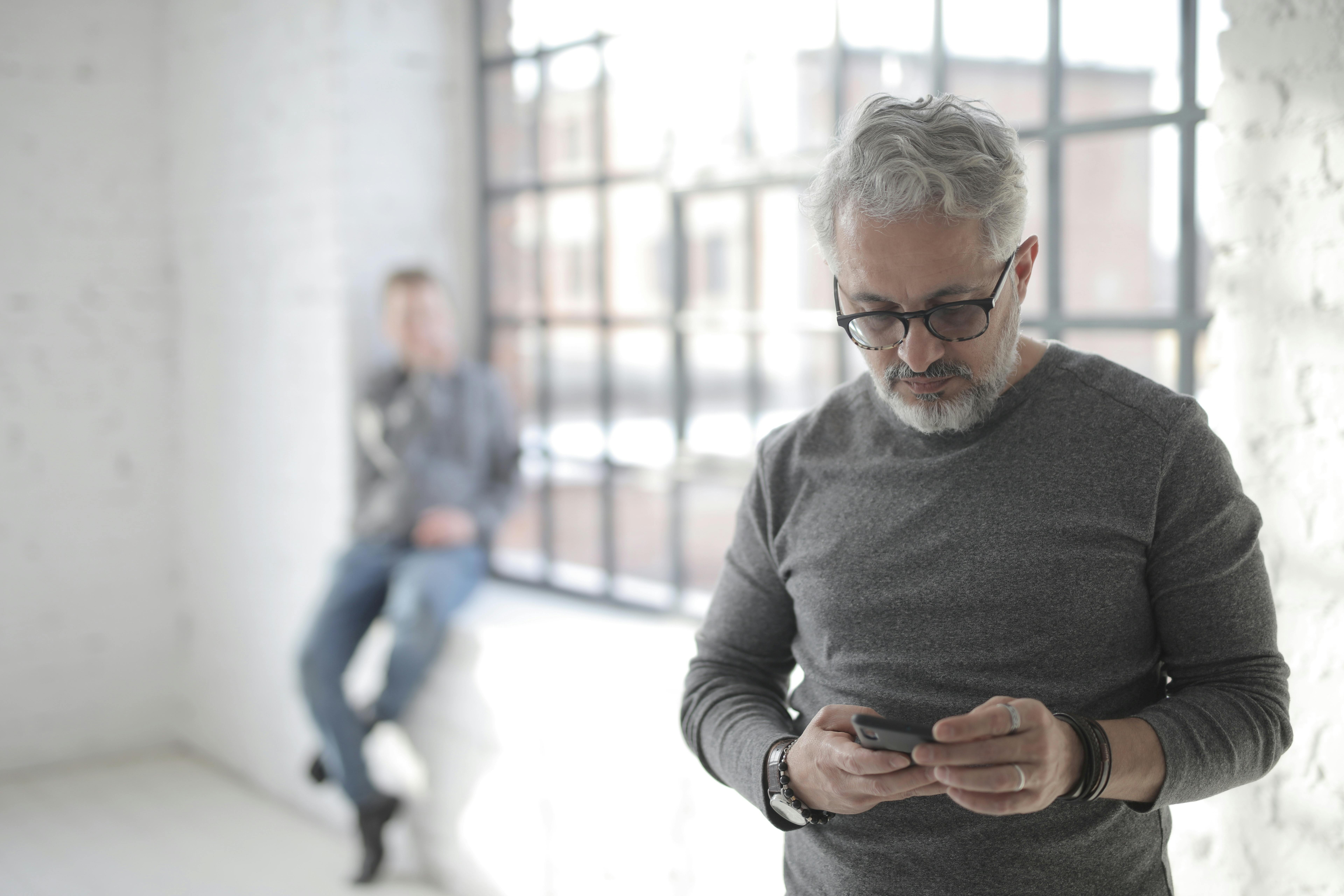 serious middle aged coworker surfing internet on smartphone