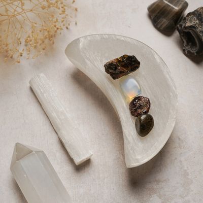 Selenite dish holding four tumbled stones beside a selenite wand, photo by Natalie Goodwin on Pexels