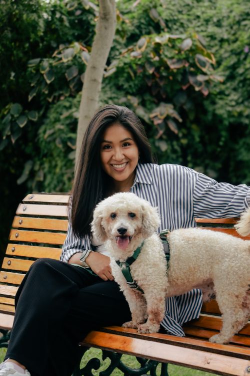 Free Happy woman sitting with dog on a bench in a lush green park. Stock Photo