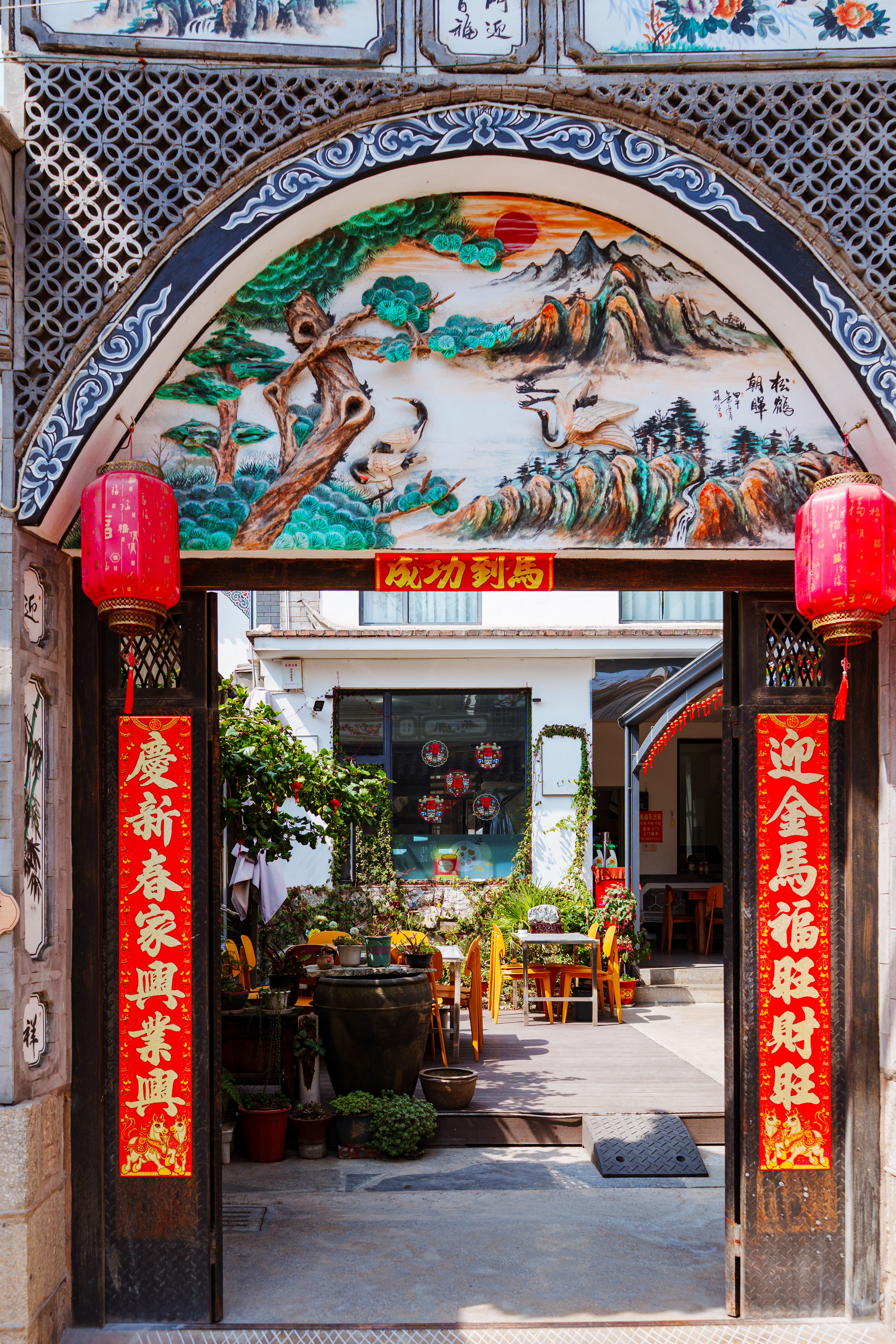 A beautifully decorated Chinese courtyard entrance with traditional red lanterns and artwork.