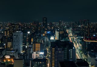 A beautiful nighttime cityscape of Osaka, Japan, with illuminated buildings and streets.