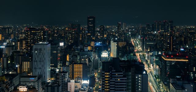 A beautiful nighttime cityscape of Osaka, Japan, with illuminated buildings and streets.