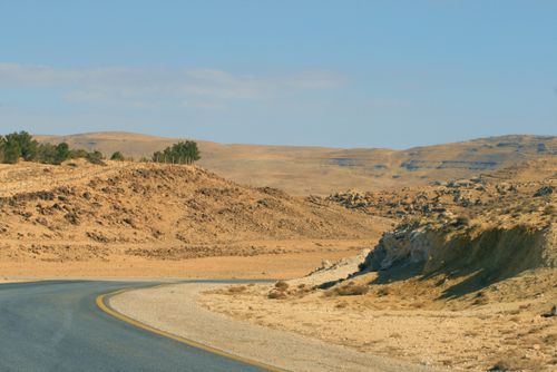 Free A serene desert road curves through rocky hills under a clear blue sky. Stock Photo