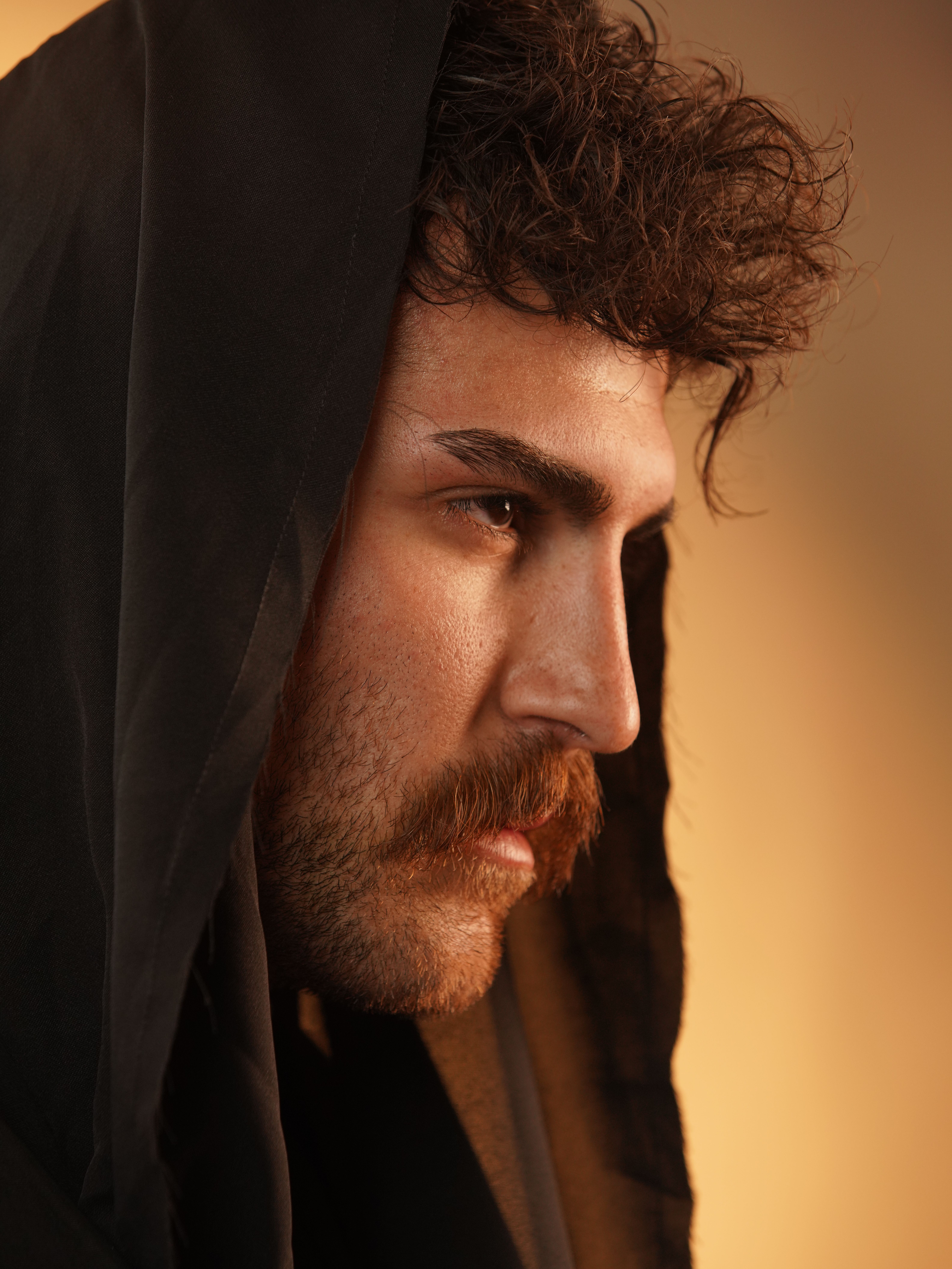 Striking profile portrait of a man in traditional attire with a warm, dramatic tone.