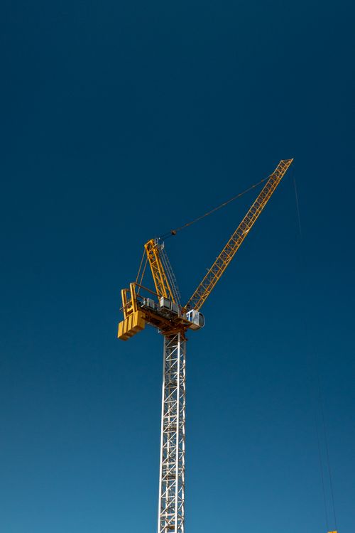 Free A towering yellow construction crane set against a clear sky, symbolizing urban development in Dubai. Stock Photo