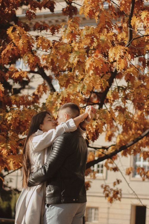 Free A couple shares a tender moment under vibrant autumn foliage, embracing the warmth of fall. Stock Photo