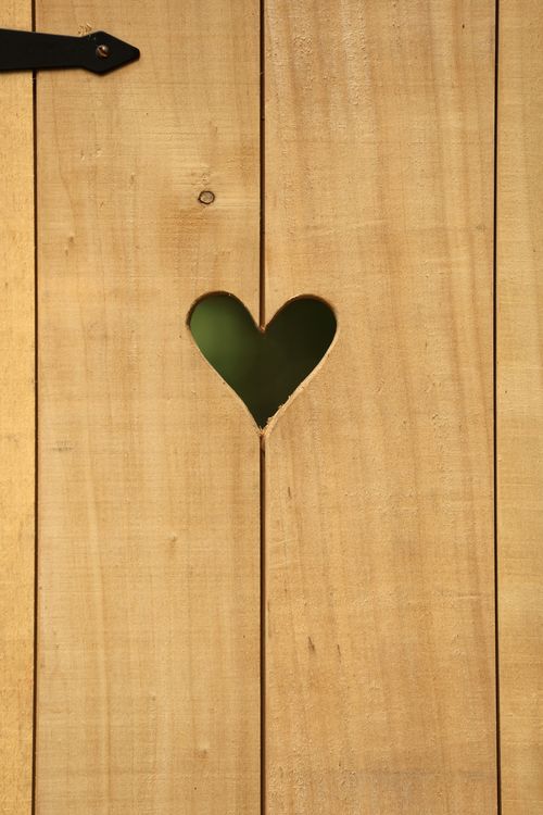 Free A close-up of a wooden fence panel featuring a heart-shaped cutout. Stock Photo