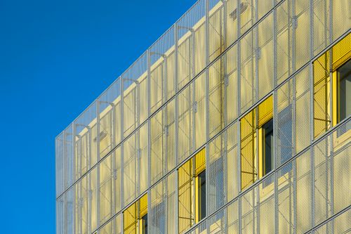 Free Close-up of a modern building facade with yellow elements and blue sky. Stock Photo