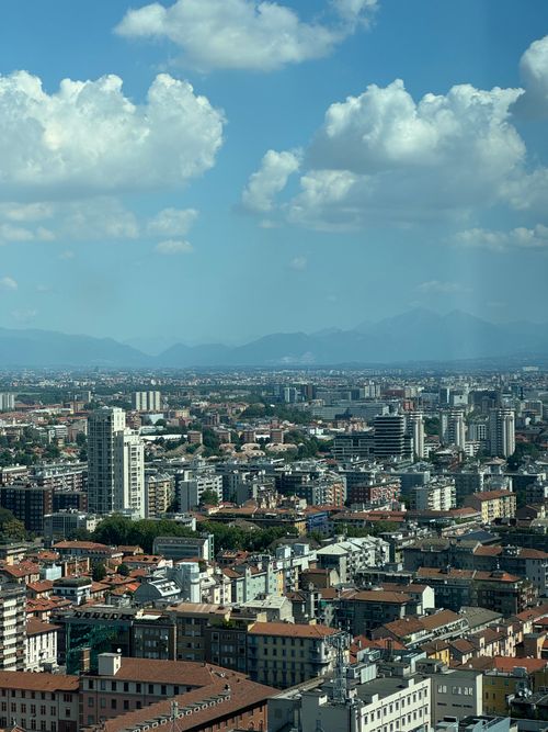 Free Stunning aerial view of Milan's skyline with distant mountains under a blue sky. Stock Photo