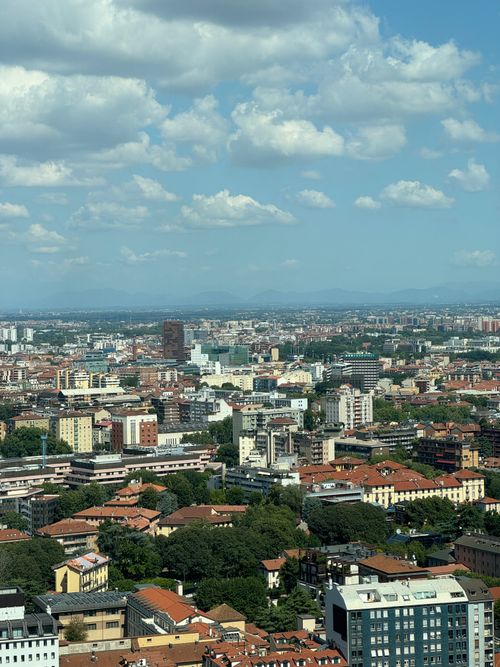 Free Aerial view of Milano's skyline with historic and modern architecture under a blue sky with clouds. Stock Photo