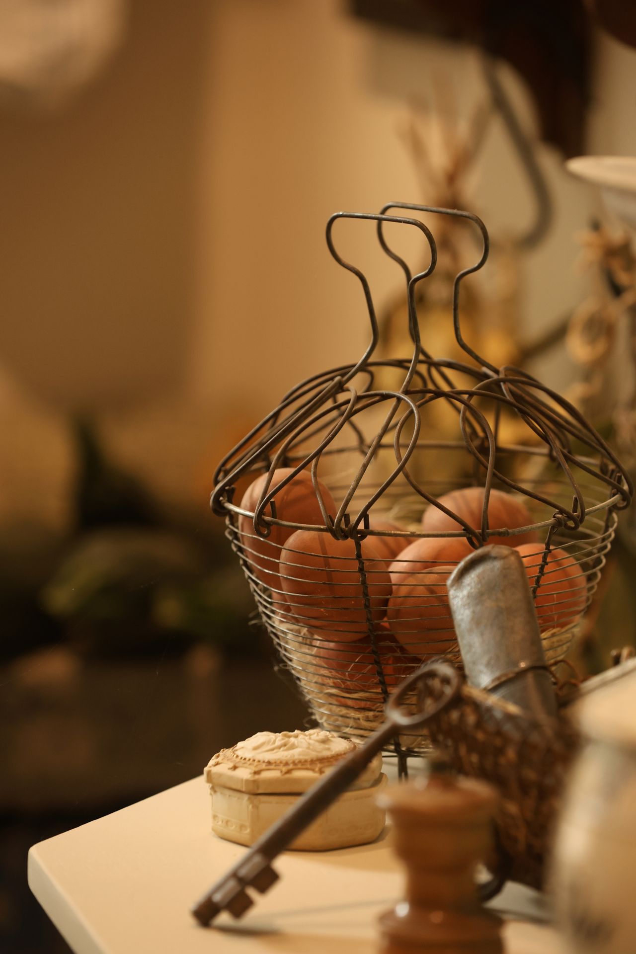 Wire egg basket with brown eggs styled with a vintage key on a farmhouse counter