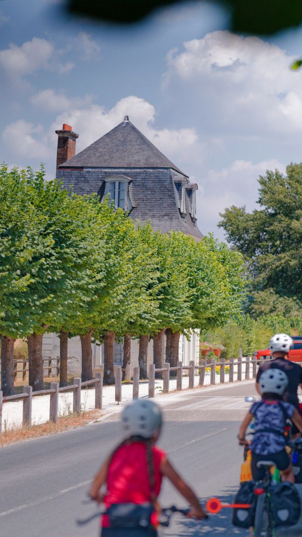 Des enfants à vélo devant un manoir au toit d'ardoise près de Villandry