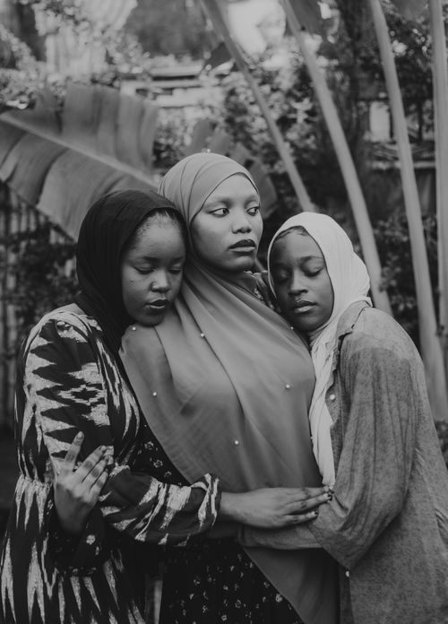 Free Black and white portrait of three women embracing, conveying unity and support. Stock Photo