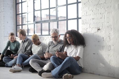 Happy multiethnic coworkers immersed in social media using smartphones