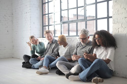 Free Happy multiracial colleagues sitting on social media using smartphones Stock Photo