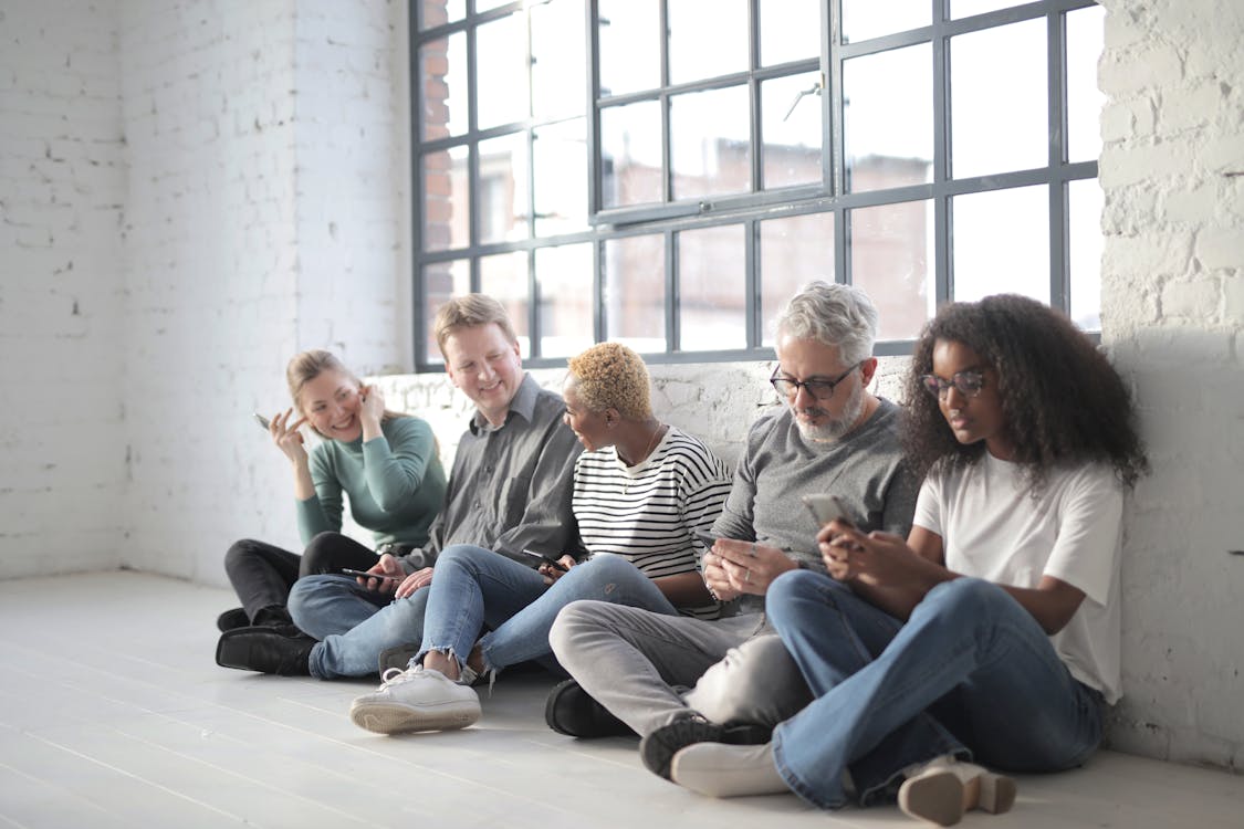 Free Happy multiracial colleagues sitting on social media using smartphones Stock Photo