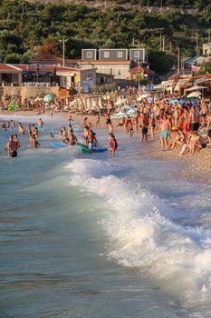 Vibrant scene of people enjoying a crowded Mediterranean beach in summer with gentle waves.