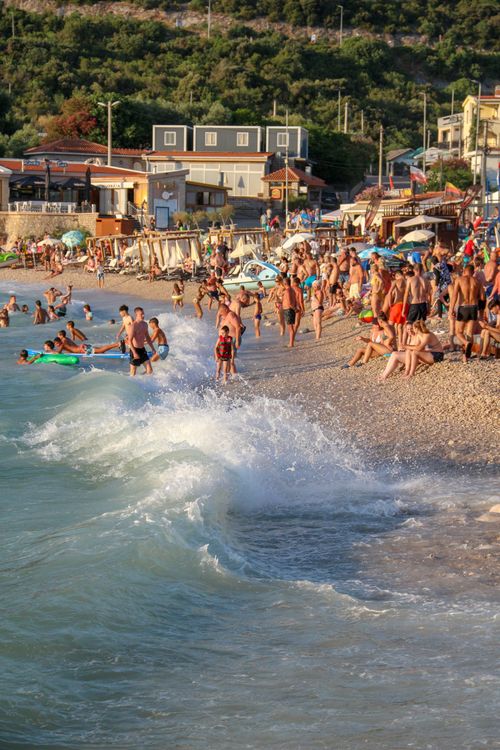 Free Vibrant beach scene with people enjoying the sunset waves along a bustling coastline. Stock Photo