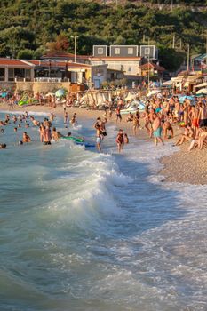 A bustling beach scene with vacationers enjoying the Mediterranean sun and waves.