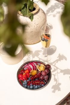Colorful fruit arrangement with berries and champagne in a bright setting.