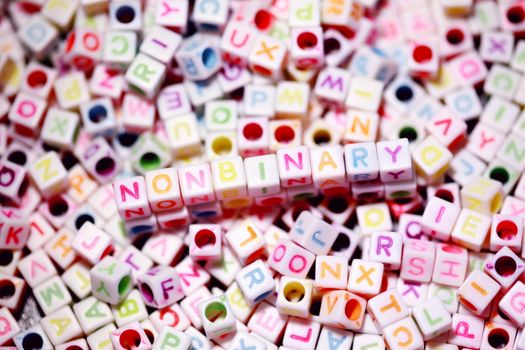 Vibrant letter beads spelling 'nonbinary' symbolize LGBTQ pride and diversity.