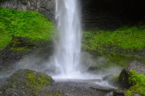 Free Beautiful waterfall cascading down surrounded by vibrant moss and rocks. Stock Photo