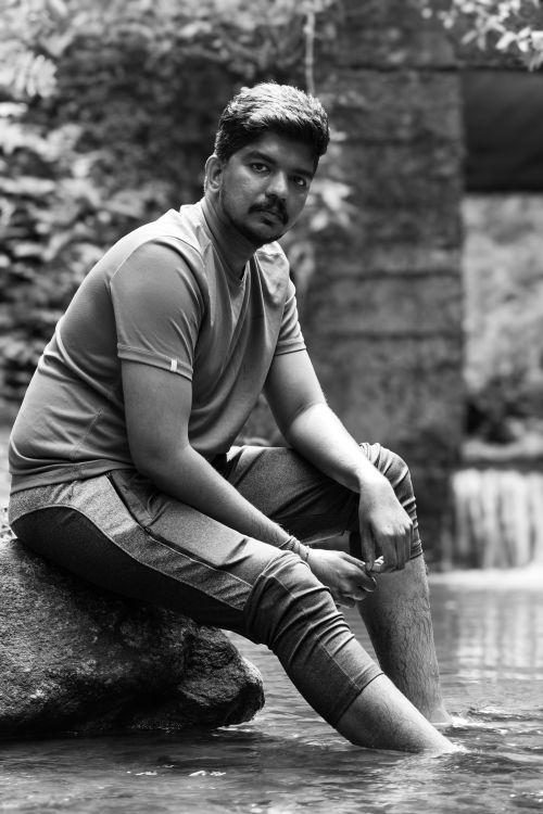 Free Black and white portrait of a man sitting by a river, conveying tranquility and contemplation. Stock Photo