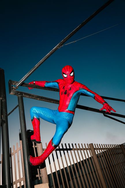 Vibrant superhero cosplay on a rooftop at dusk. Energetic and dynamic pose.