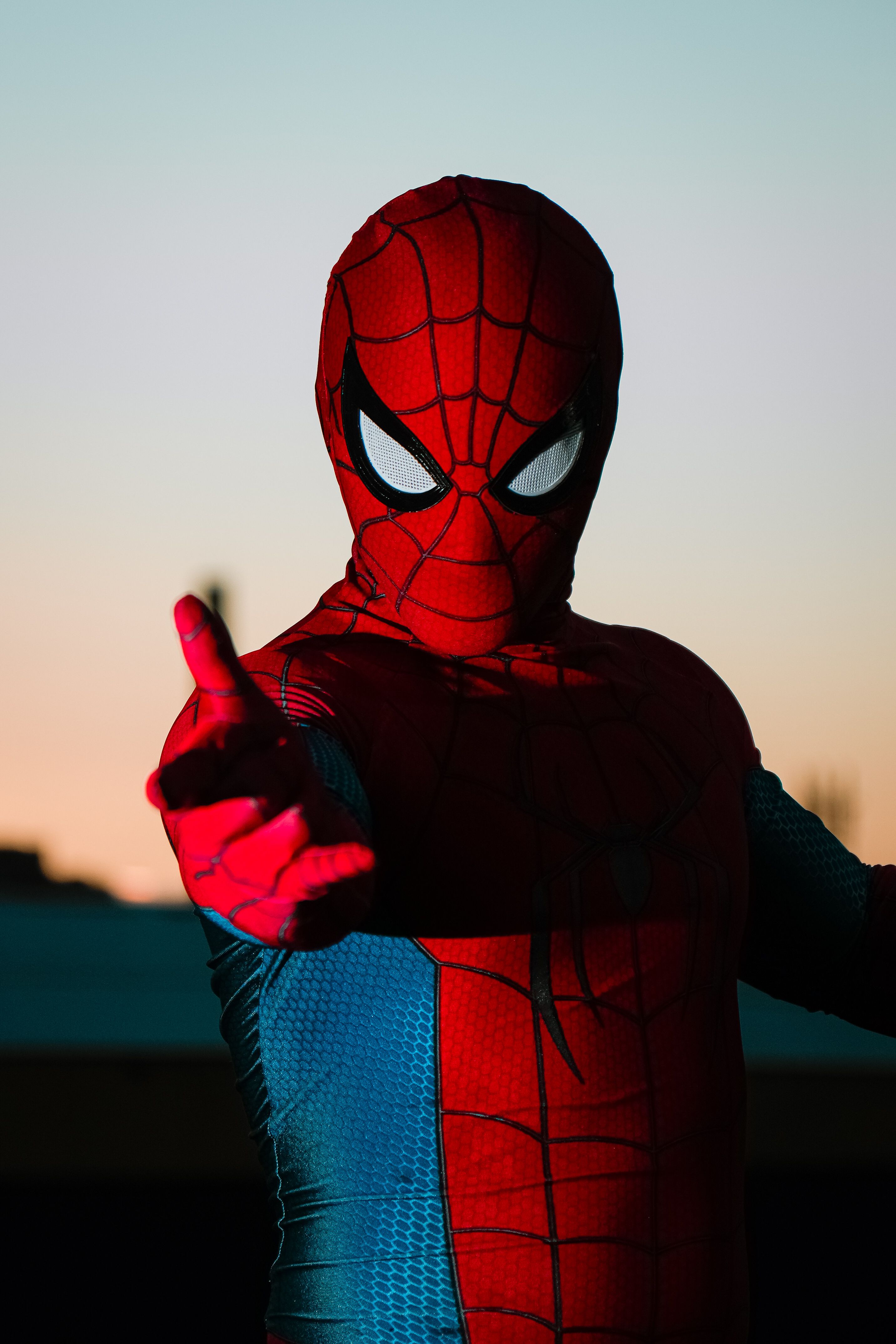 Person in superhero costume posing at sunset, vibrant colors, dynamic stance.
