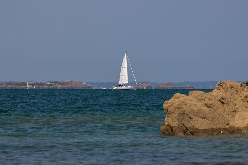 Voilier longeant une côte rocheuse près de Saint-Malo
