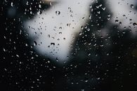 雨滴在玻璃窗上的特写镜头，背景黑暗而模糊