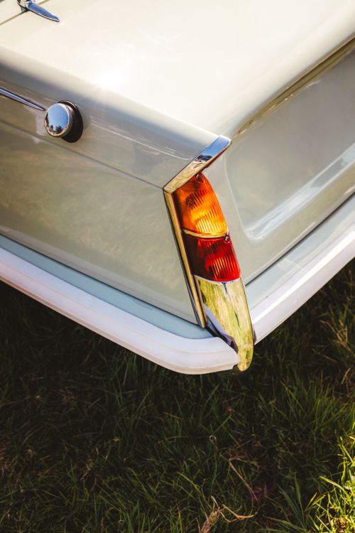 Free Close-up of a classic car's rear showcasing chrome accents and tail light on a sunny day. Stock Photo
