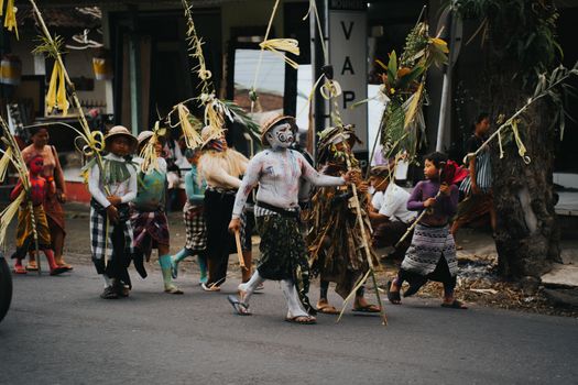 Colorful Ngerebeg parade with children in costumes and face paint in Ubud, Bali, showcasing vibrant cultural traditions.