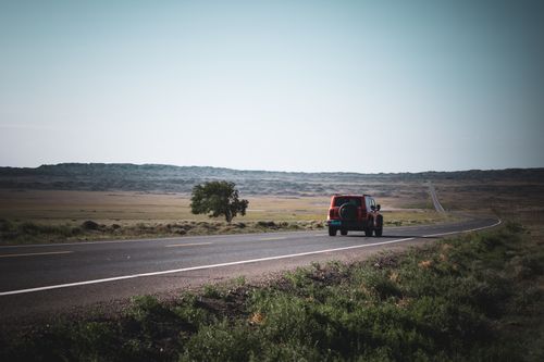 Free A red SUV travels on a scenic open road in Xinjiang, China, under clear daylight skies. Stock Photo