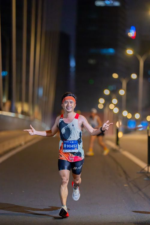 Free Smiling runner at night marathon in city, wearing race bib. Stock Photo