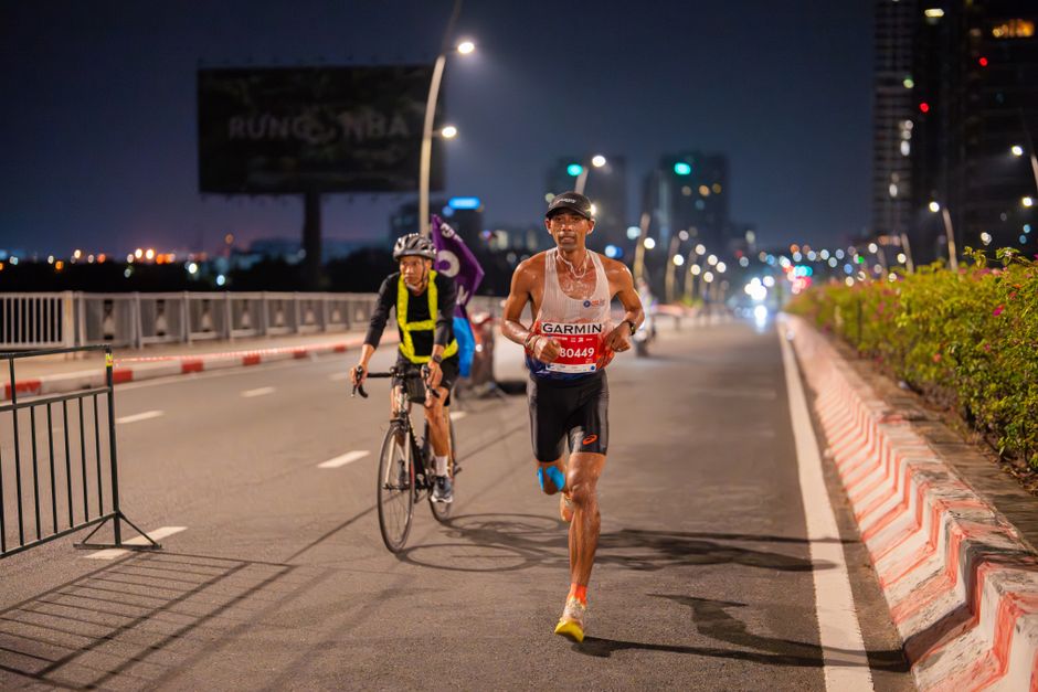 Marathon runner and cyclist participate in a vibrant night city race.