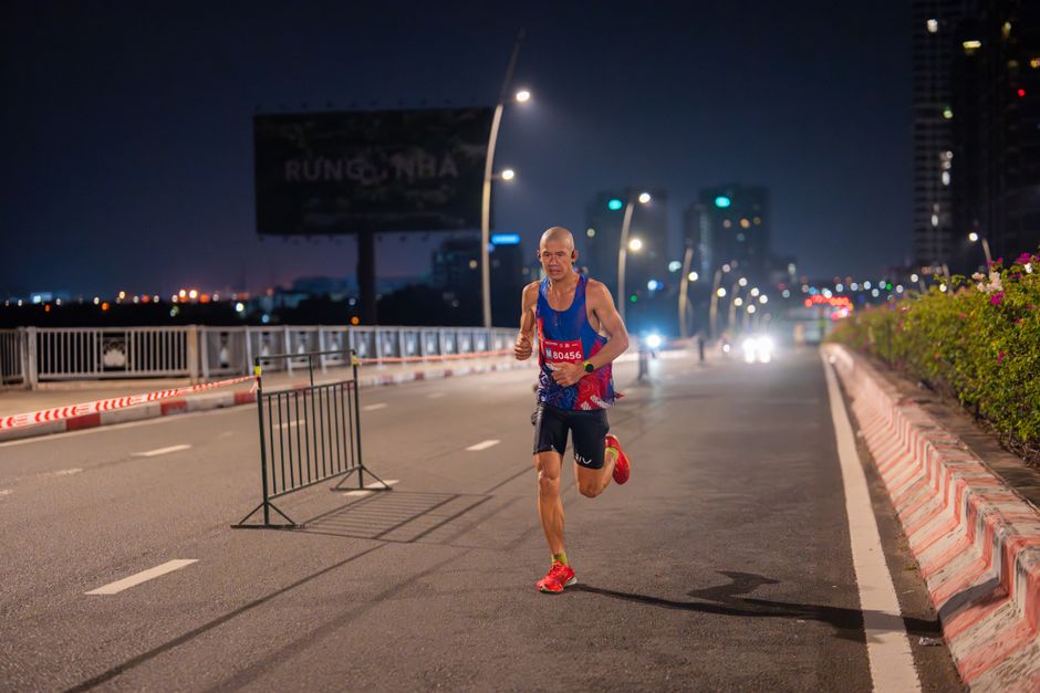 A focused runner competes in an urban marathon at night, road illuminated by streetlights.
