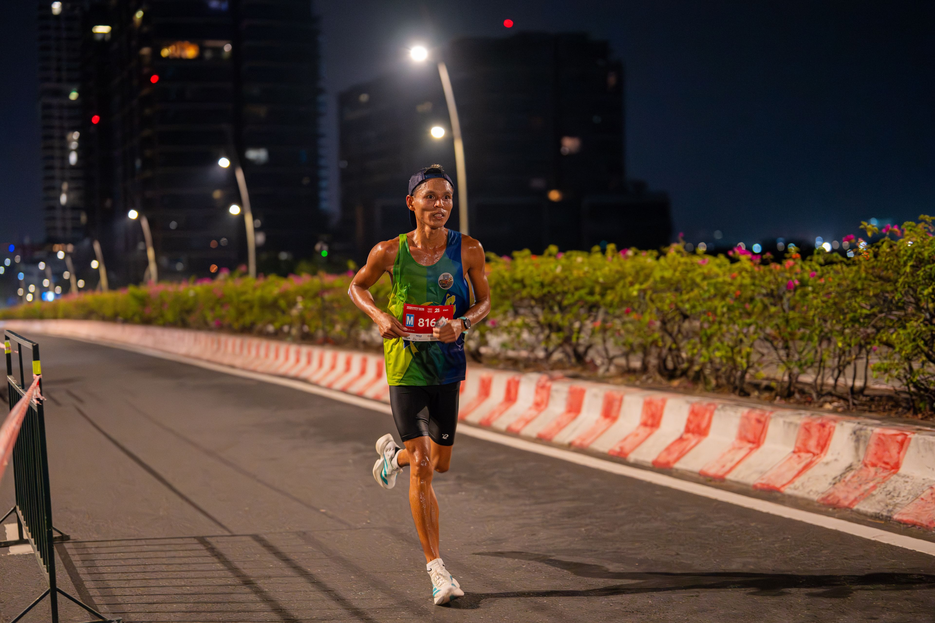 A male runner competes in a nighttime city marathon, showcasing endurance.
