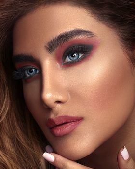 Close-up portrait of a woman with striking blue eyes and bold makeup.