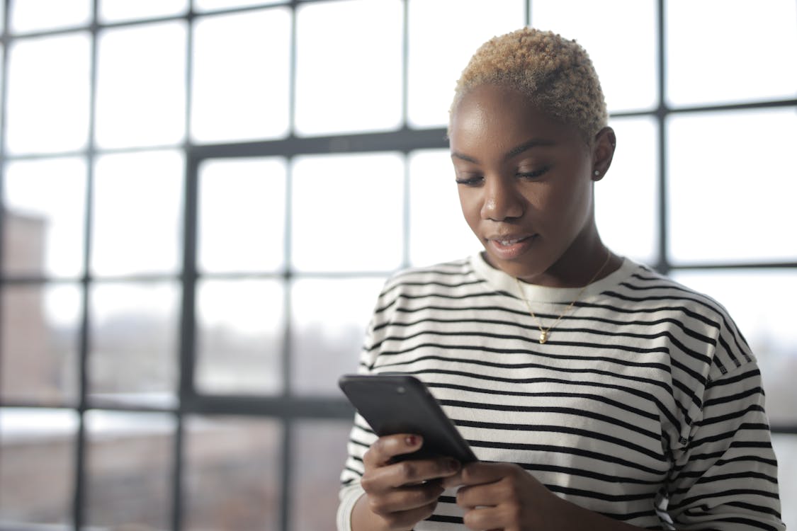 Woman in White and Black Striped Crew Neck Shirt Holding Black Smartphone