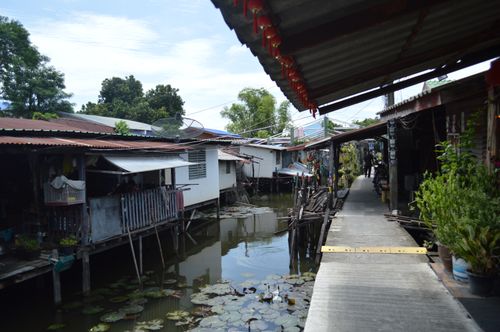 Free Explore a serene riverside village with traditional stilt houses along a narrow waterway. Stock Photo